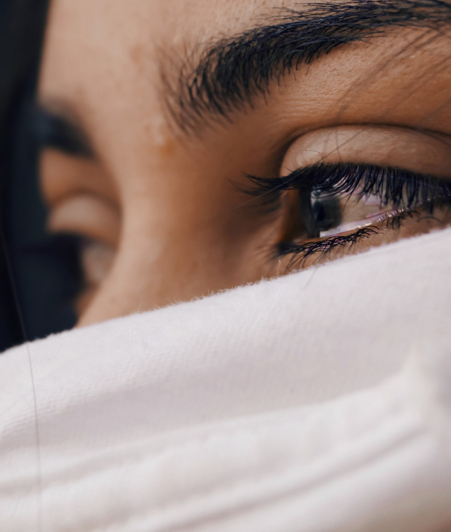 Close-up of a woman&rsquo;s eye above a white blanket pulled up to her face