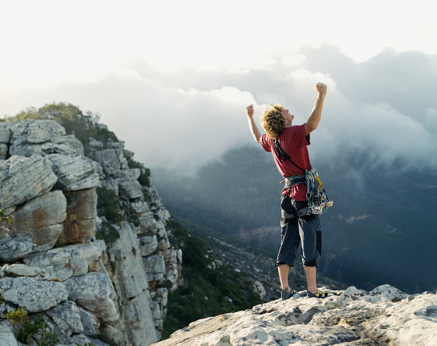 A hiker celebrating at a mountain summit